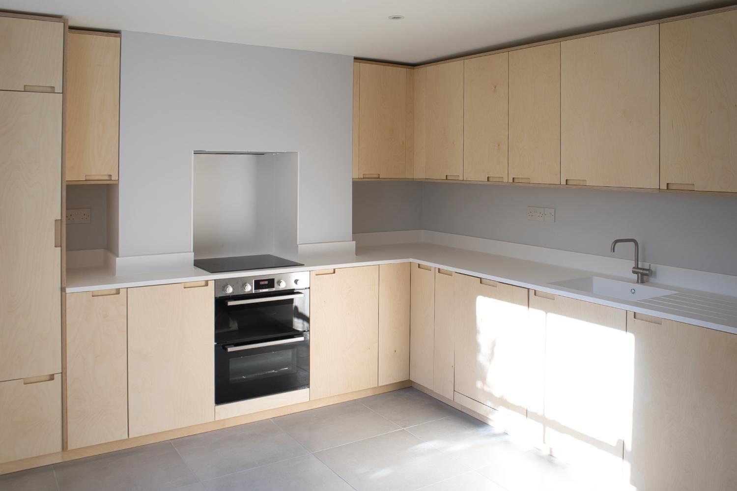 Birch ply kitchen with grey floor tiles and blue walls
