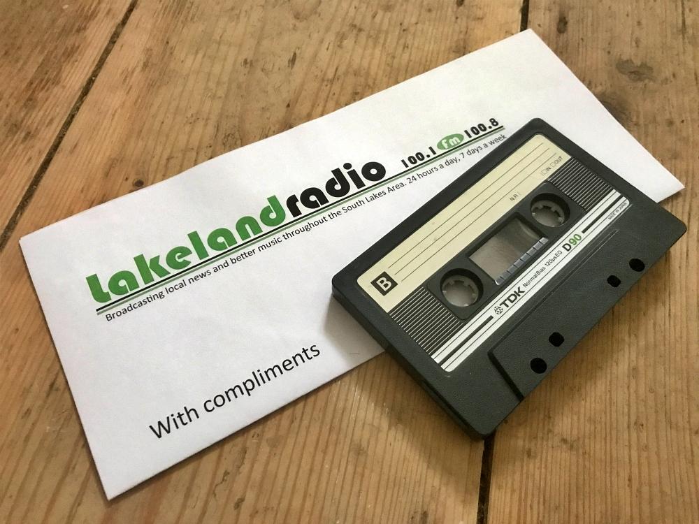 Lakeland Radio compliments slip and an audio cassette on wooden floorboards
