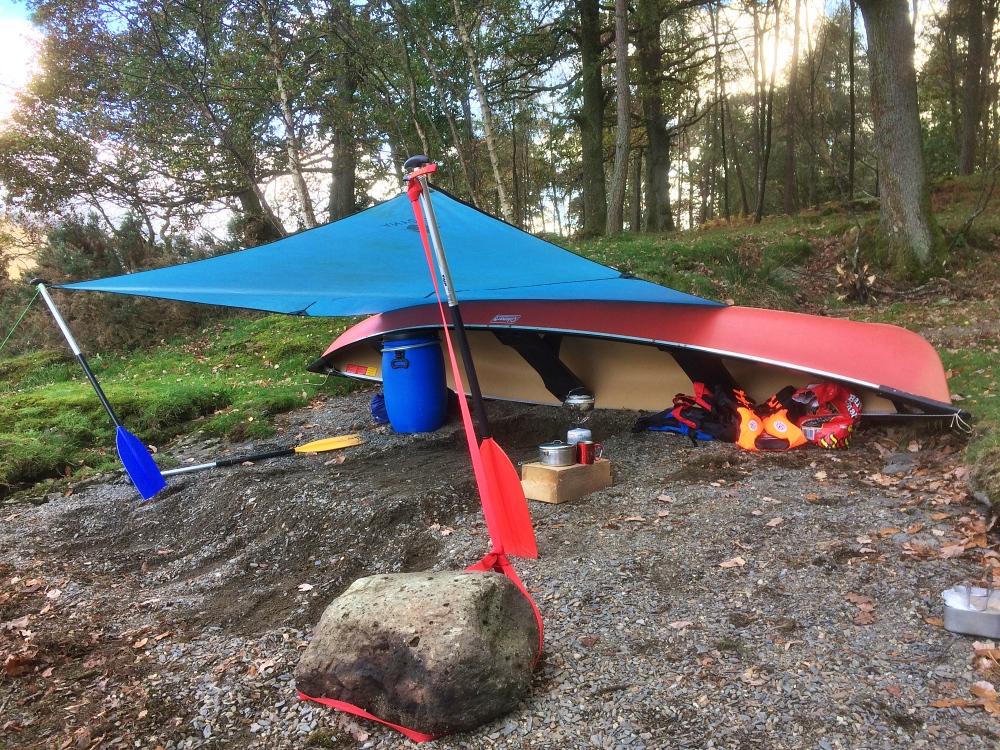Canoe on the shore of Derwentwater with a tarp shelter tied to two paddles