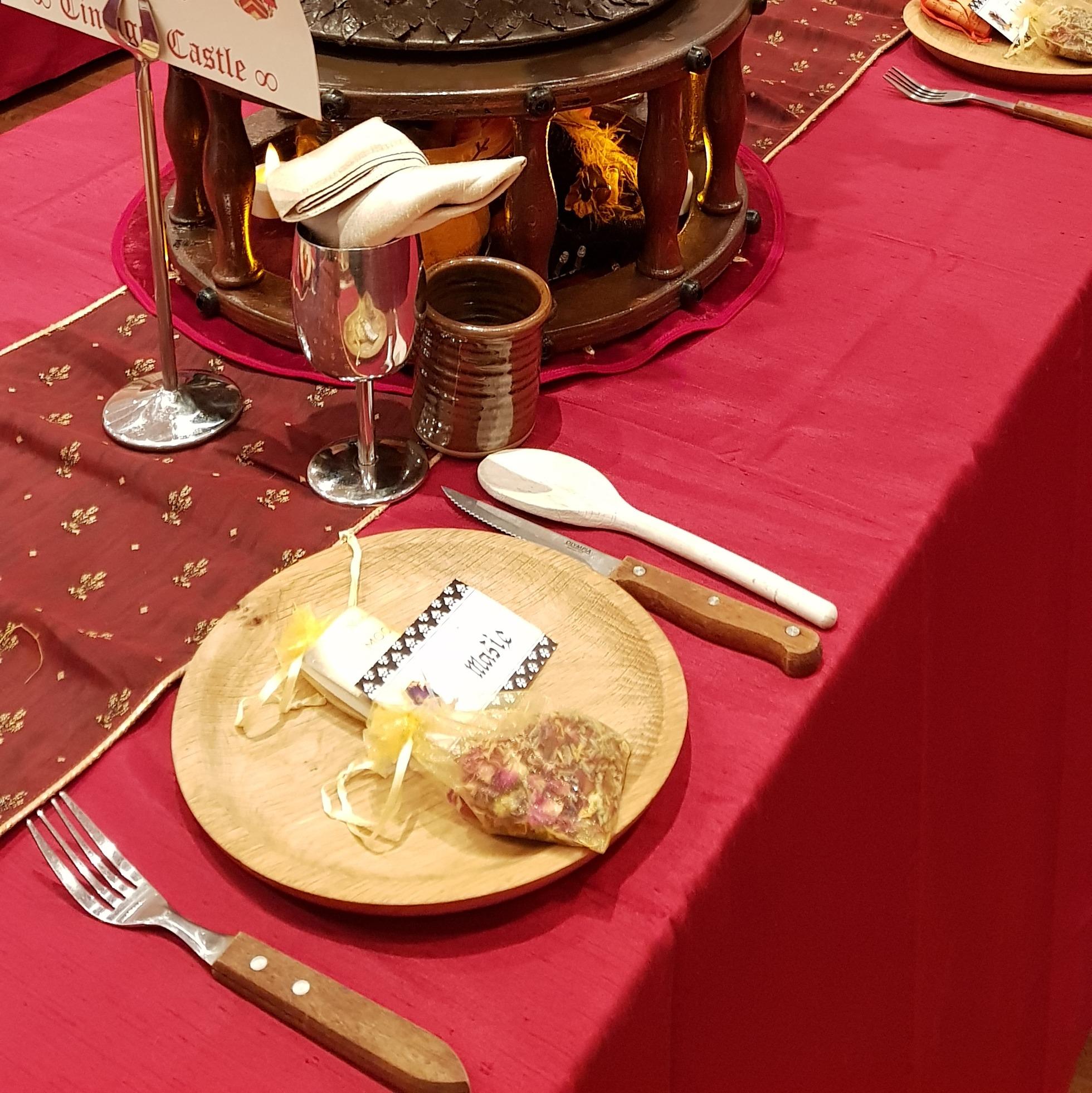 Wooden plate in a burgundy table dressing at Medieval Banquet