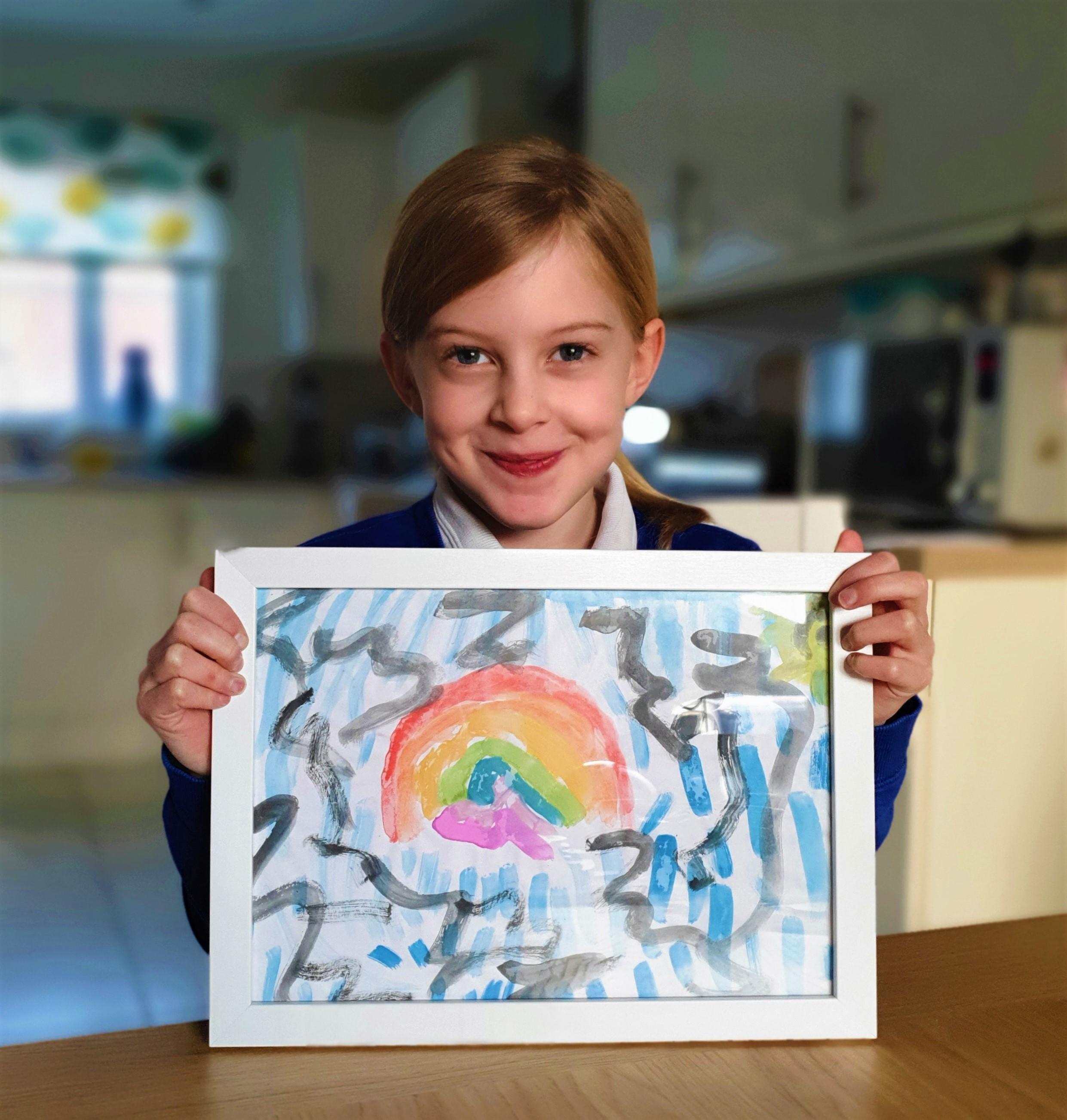 photo of a girl holding a painting of a rainbow
