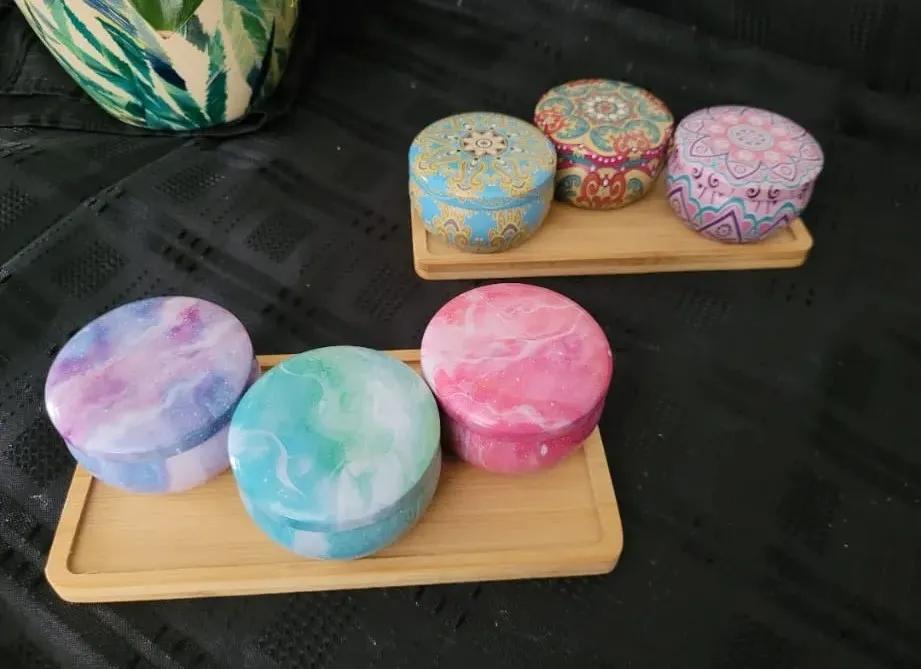 Two sets of three candle tins on a bamboo tray.